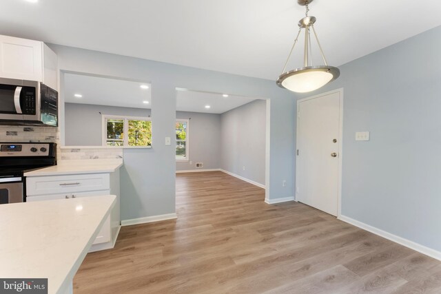 kitchen featuring white cabinetry, tasteful backsplash, stainless steel appliances, and light wood-type flooring