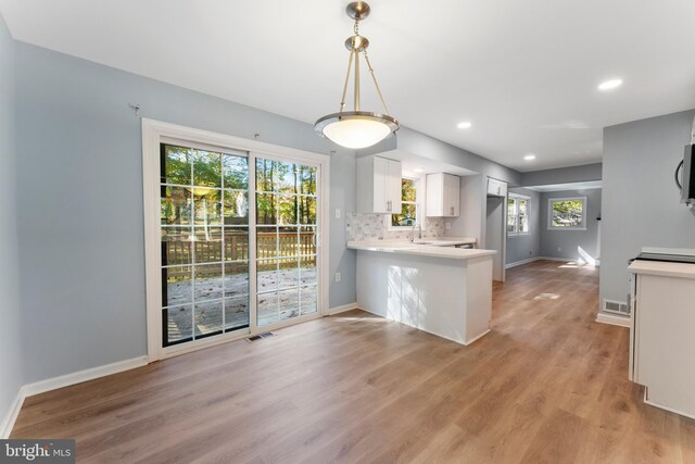 kitchen featuring a wealth of natural light, white cabinets, kitchen peninsula, and light wood-type flooring