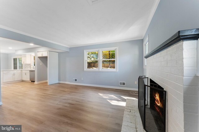 unfurnished living room featuring ornamental molding, light hardwood / wood-style flooring, and a fireplace