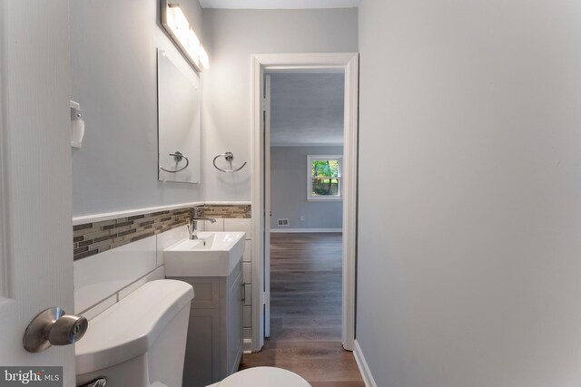 bathroom featuring vanity, toilet, wood-type flooring, and backsplash