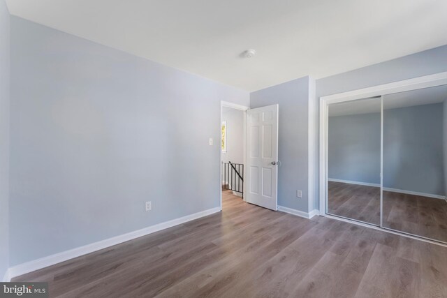 unfurnished bedroom with a closet and hardwood / wood-style floors