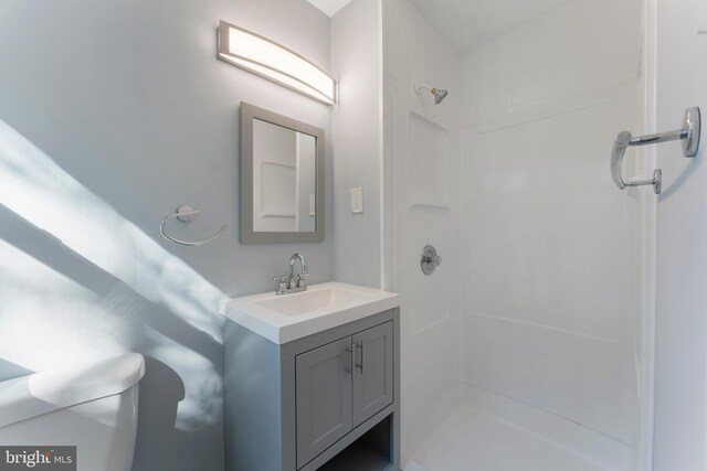 bathroom with toilet, vanity, and a shower