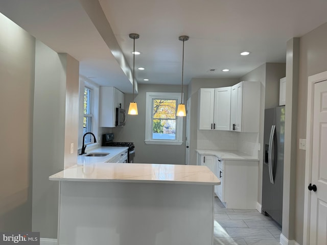 kitchen featuring white cabinetry, appliances with stainless steel finishes, sink, and kitchen peninsula