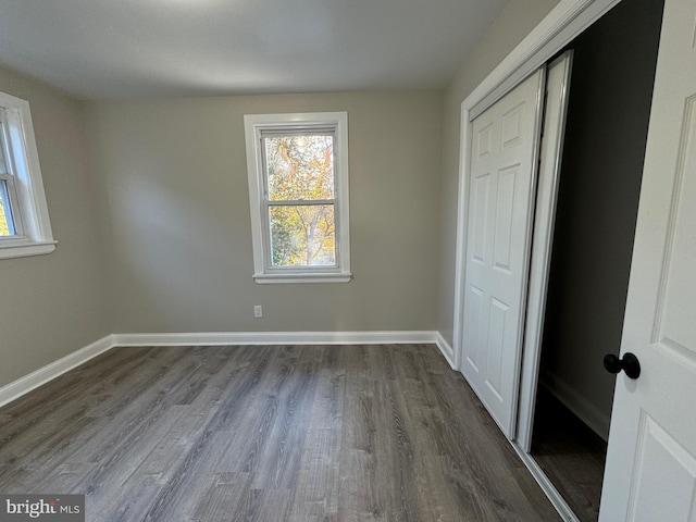 unfurnished bedroom with a closet and dark hardwood / wood-style flooring