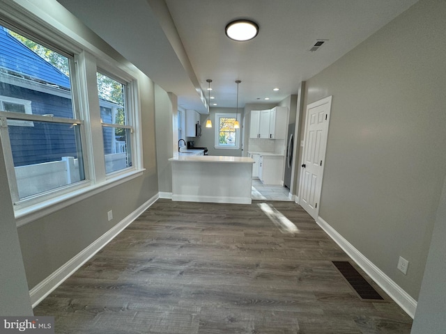 kitchen featuring hardwood / wood-style flooring, a wealth of natural light, kitchen peninsula, and white cabinets