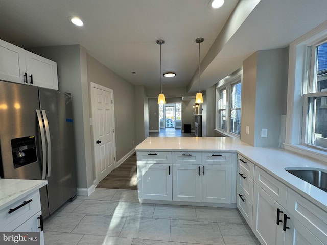 kitchen with kitchen peninsula, white cabinetry, light wood-type flooring, stainless steel refrigerator with ice dispenser, and decorative light fixtures