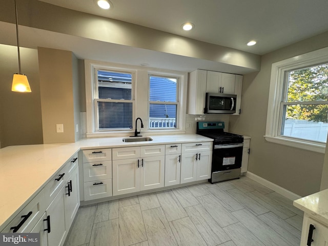 kitchen featuring sink, kitchen peninsula, stainless steel appliances, pendant lighting, and white cabinets