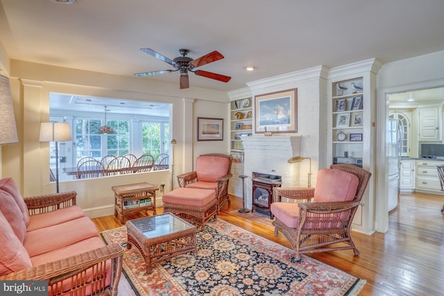 sitting room with built in features, decorative columns, light wood-type flooring, and ceiling fan