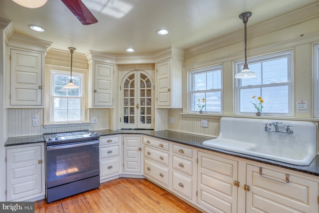 kitchen featuring sink, light wood-type flooring, pendant lighting, and electric stove