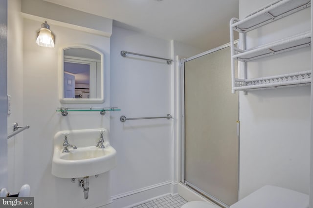 bathroom featuring toilet, a shower with shower door, sink, and tile patterned flooring