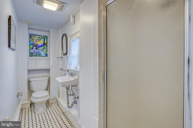 bathroom featuring toilet, walk in shower, and tile patterned flooring