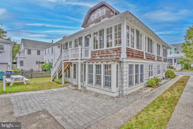 rear view of house featuring a patio area, a lawn, and a sunroom