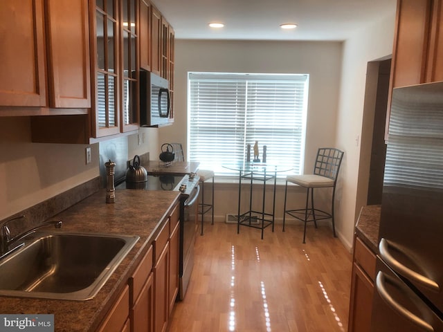 kitchen with sink, stainless steel appliances, and light wood-type flooring