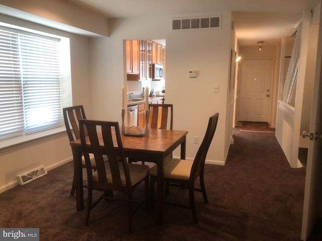 dining space featuring a wealth of natural light and dark colored carpet