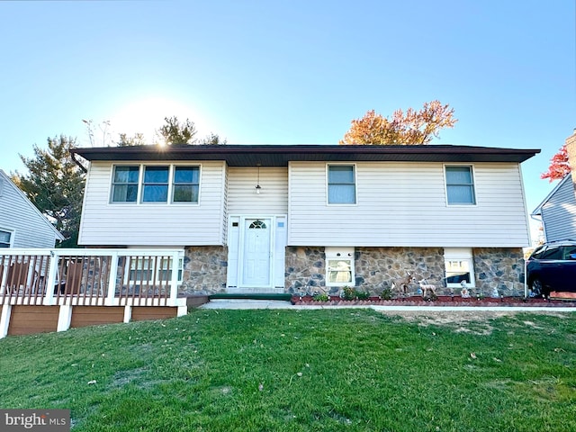 raised ranch with a wooden deck and a front lawn