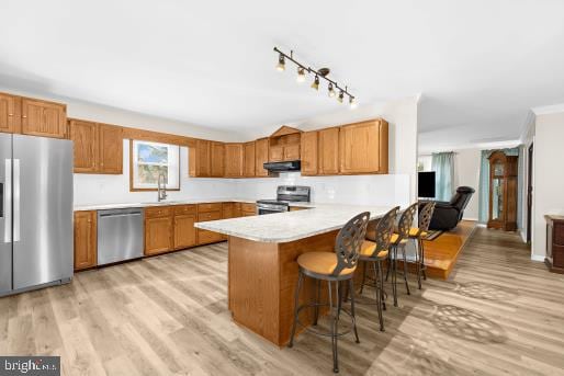 kitchen featuring appliances with stainless steel finishes, light wood-type flooring, a kitchen bar, kitchen peninsula, and rail lighting