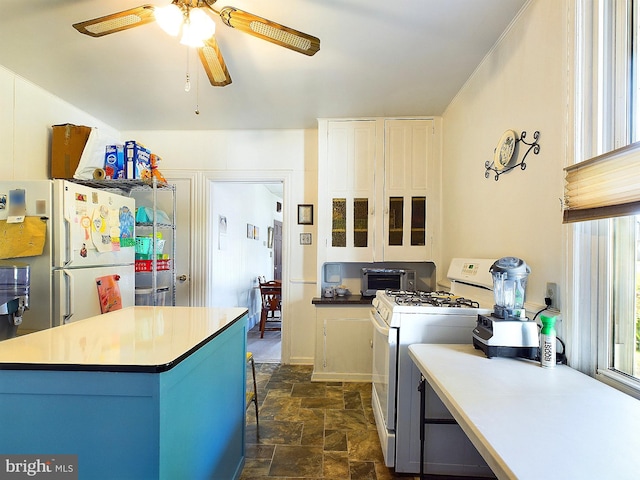 kitchen featuring a center island, white cabinets, white appliances, and ceiling fan