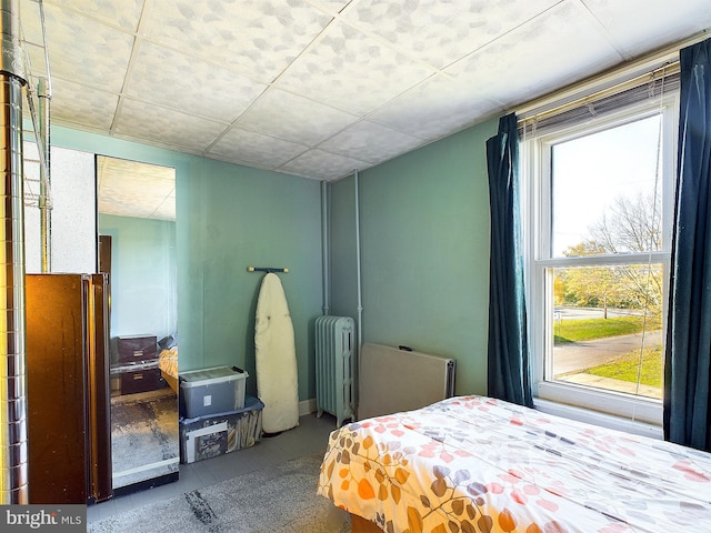 bedroom with multiple windows, radiator heating unit, and tile patterned flooring