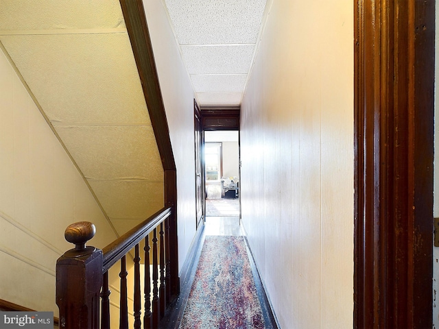 hall with wooden walls and a paneled ceiling