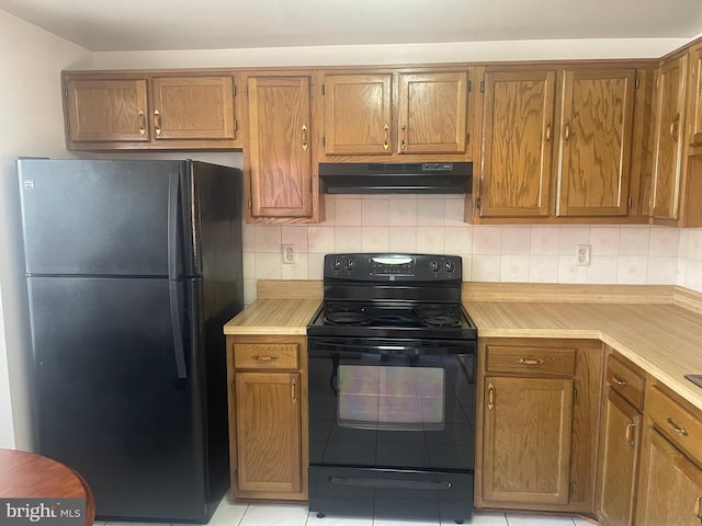 kitchen with light tile patterned flooring, black appliances, and backsplash