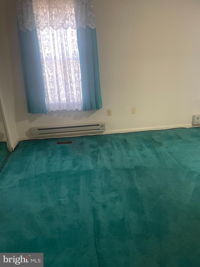 unfurnished room featuring a baseboard heating unit and carpet flooring