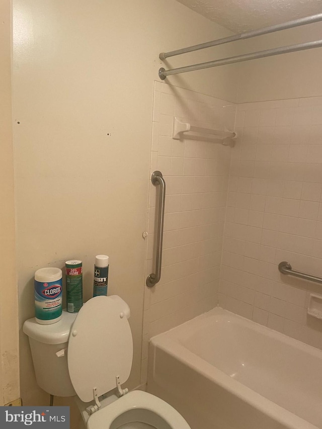 bathroom with toilet, tiled shower / bath combo, and a textured ceiling