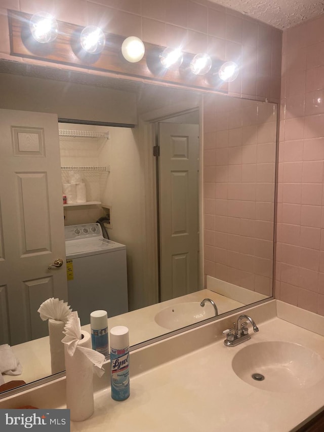 bathroom featuring vanity, a textured ceiling, and washer / clothes dryer