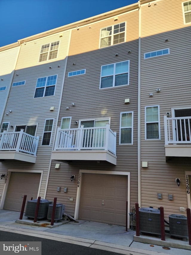 back of house featuring a balcony, central AC, and a garage