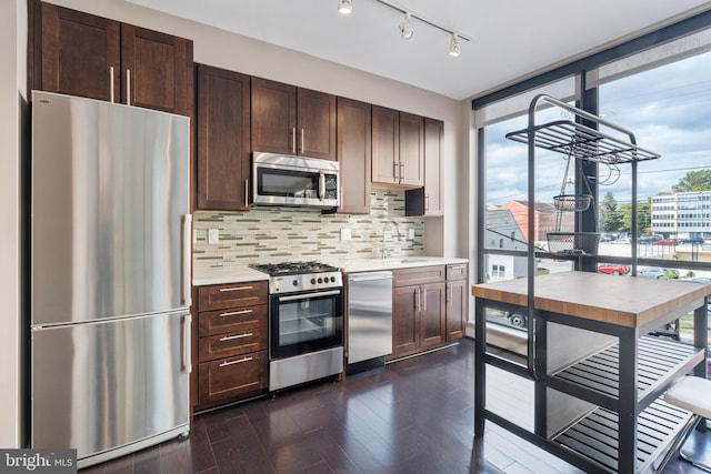 kitchen featuring tasteful backsplash, appliances with stainless steel finishes, dark hardwood / wood-style floors, dark brown cabinetry, and sink