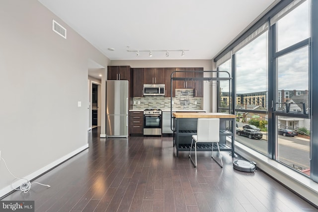 kitchen featuring decorative backsplash, dark brown cabinets, butcher block counters, dark wood-type flooring, and stainless steel appliances