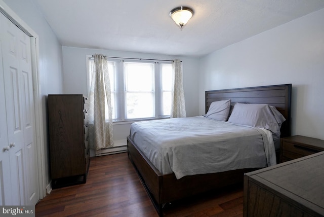 bedroom featuring baseboard heating, dark hardwood / wood-style floors, and a closet