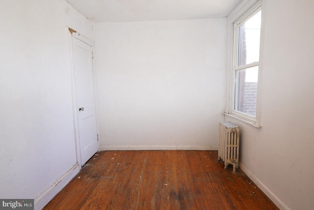 unfurnished room featuring radiator and dark hardwood / wood-style flooring