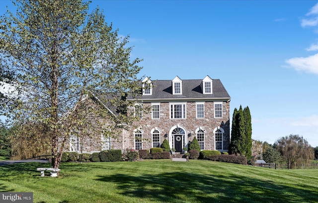 colonial-style house with stone siding and a front yard