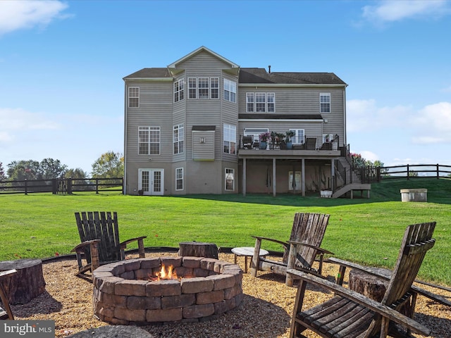 rear view of property with a lawn, fence, an outdoor fire pit, french doors, and a wooden deck