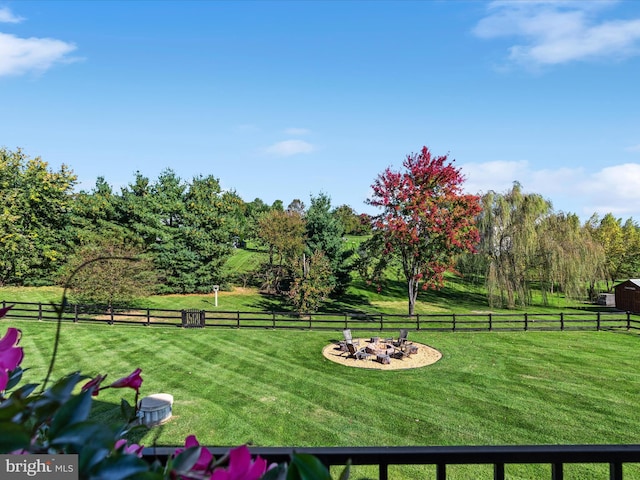 view of yard with a rural view, an outdoor fire pit, and fence