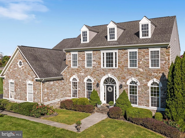 view of front facade featuring a front lawn and roof with shingles