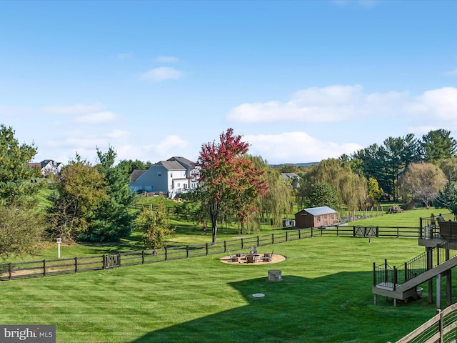 view of home's community with an outbuilding, a yard, fence, and an outdoor fire pit