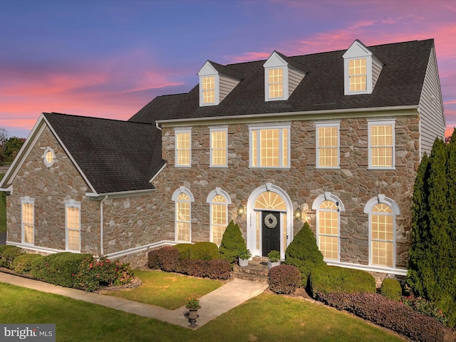 view of front of house featuring a lawn and roof with shingles