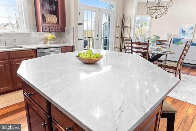 kitchen featuring dishwasher, a breakfast bar, light wood-type flooring, decorative backsplash, and a sink