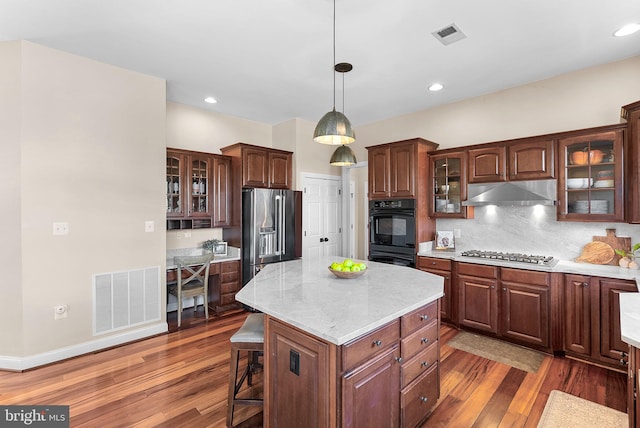 kitchen featuring wood finished floors, visible vents, under cabinet range hood, and stainless steel appliances