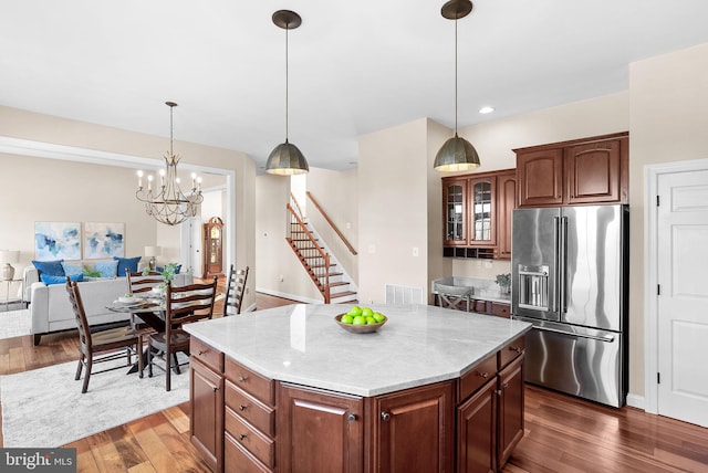 kitchen with visible vents, dark wood-type flooring, high end fridge, decorative light fixtures, and glass insert cabinets