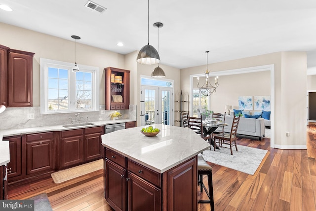 kitchen featuring visible vents, decorative backsplash, french doors, light wood-style floors, and a sink