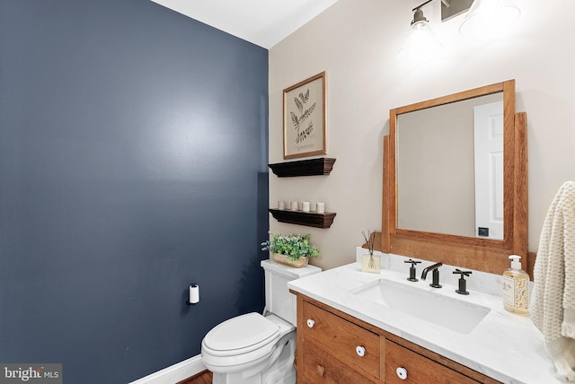 bathroom featuring baseboards, toilet, and vanity