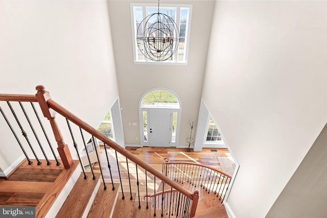 entrance foyer featuring baseboards, stairs, a high ceiling, wood finished floors, and a notable chandelier