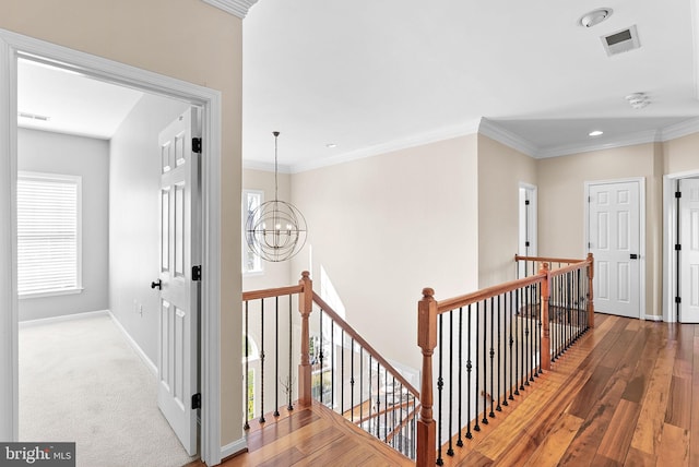 hall featuring hardwood / wood-style floors, a notable chandelier, an upstairs landing, and visible vents