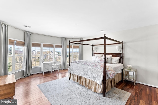 bedroom with visible vents, baseboards, and wood finished floors