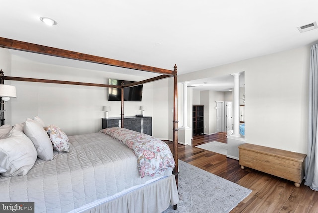 bedroom with visible vents, wood finished floors, and ornate columns