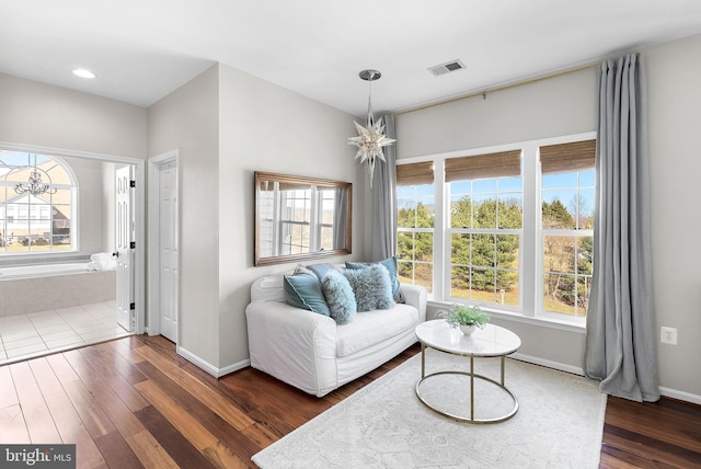 living room with visible vents, baseboards, an inviting chandelier, and wood finished floors