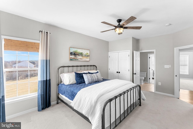 bedroom featuring multiple windows, light carpet, baseboards, and a ceiling fan