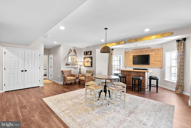 dining space with recessed lighting, a dry bar, baseboards, and wood finished floors